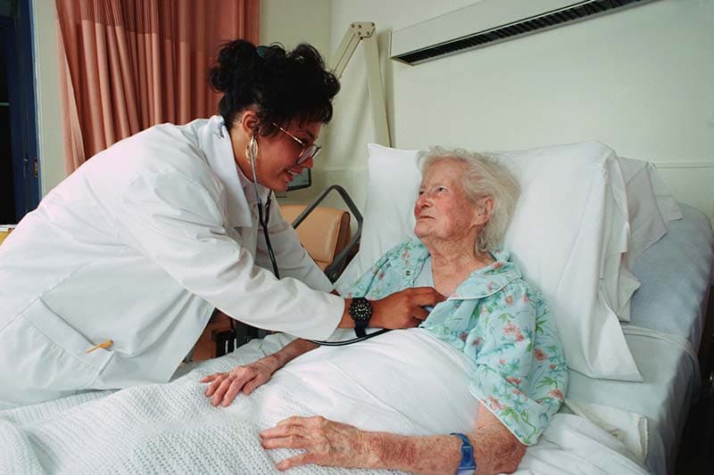 A clinician at the bedside of an elderly patient, evoking Medi-Cal long-term care.